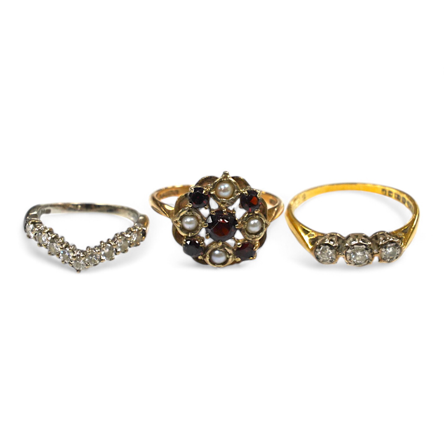 Two 18ct gold and diamond set rings including chevron shape and a 9ct gold, garnet and seed pearl set ring. Condition - fair